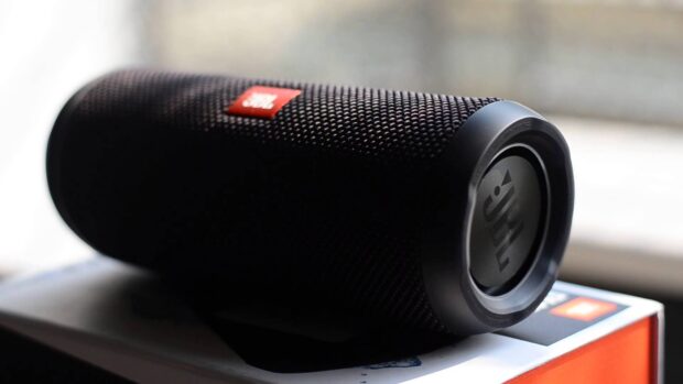 A portable black JBL speaker resting on a box indoors, HD Desktop Wallpaper