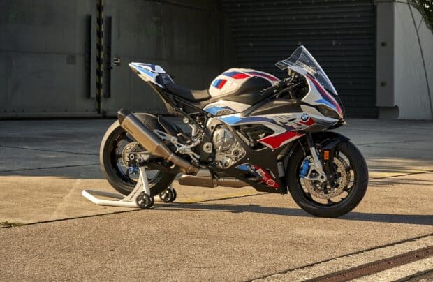 A white BMW M 1000 RR motorcycle is parked on a stand in an industrial area, HD Desktop Wallpaper