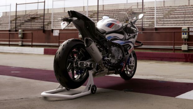 A BMW M 1000 RR motorcycle is shown standing on a trackside stand at a racetrack, HD Desktop Wallpaper