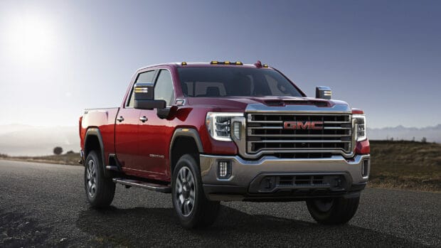 A powerful Gmc Sierra pickup truck is parked on the road with mountains in the background, 2K Desktop Wallpaper
