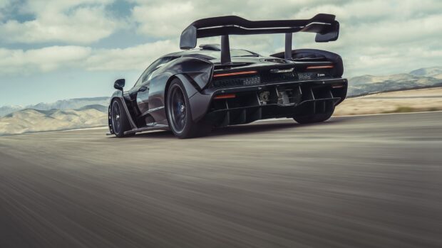 A black Mclaren Senna driving fast on an open road with mountains in the background, HD Desktop Wallpaper