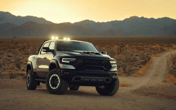A powerful Ram pickup is parked on a dirt road with mountains in the background, 2K Desktop Wallpaper