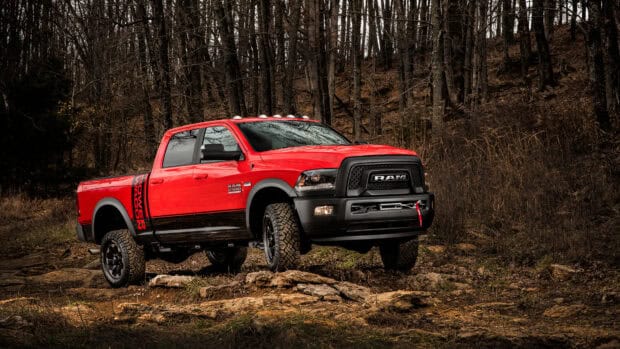 A powerful Ram Pickup is parked on rocky ground surrounded by leafless trees in the forest, 4K Desktop Wallpaper