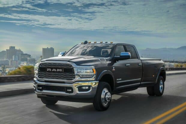 A black Ram Pickup is driving through a city street under a cloudy sky, 2K Desktop Wallpaper