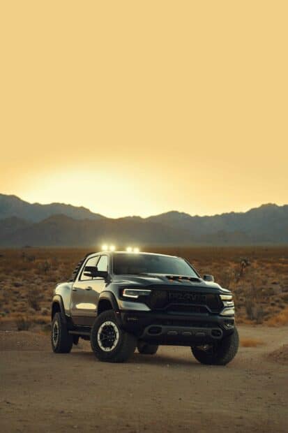 A powerful Ram Truck drives on a desert road with mountains and sunset in the background, HD Phone Wallpaper