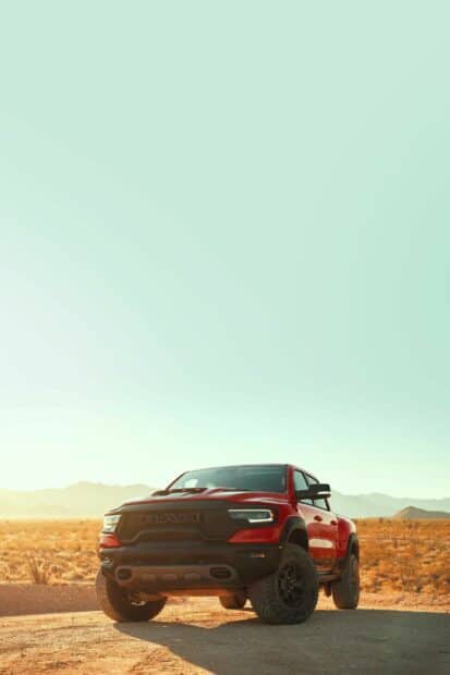 A red Ram truck is parked on a desert road with mountains in the background under a clear sky, HD Mobile Wallpaper