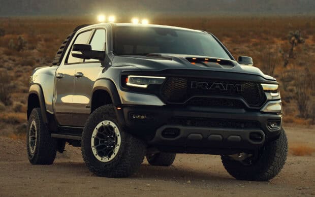 A powerful Ram truck is parked on rough desert terrain at dusk with lights on, HD Desktop Wallpaper