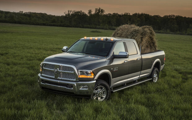 A powerful Ram truck is parked in a green field carrying hay at dusk, 2K Desktop Wallpaper