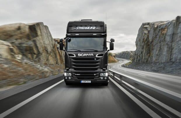 A black Scania truck drives through a winding mountain road under a cloudy sky, HD Desktop Wallpaper