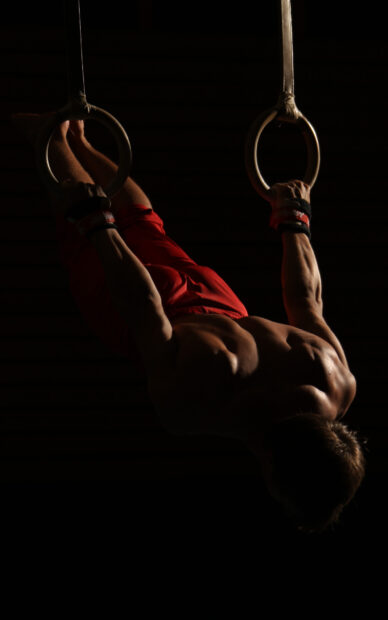 A gymnast demonstrates acrobatic gymnastics strength on rings, HD Desktop Wallpaper