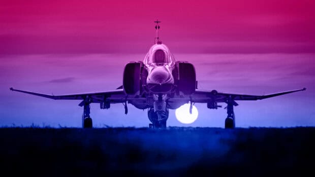 A jet fighter is positioned on the runway with a colorful sky and sun setting in the background, 4K Desktop Wallpaper
