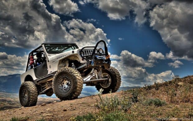 A rugged off road vehicle climbs a dirt hill under a cloudy sky in off road driving wallpapers, HD Desktop Wallpaper