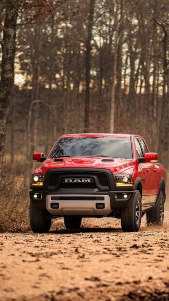 A red Ram truck moves along a dirt road in a dense forest during autumn, HD Mobile Wallpaper