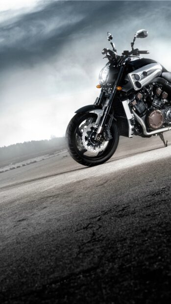 A powerful street bike is parked on an empty road under a cloudy sky with visible details, 4K Phone Wallpaper