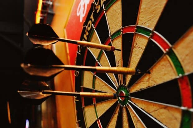 Three darts perfectly hit the bullseye on the dartboard during a game, HD Desktop Wallpaper