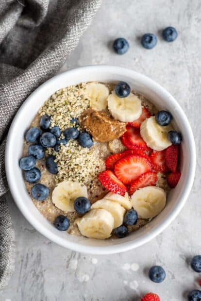 A bowl of quinoa with banana, strawberry, blueberry, and seeds on a table, HD Mobile Wallpaper