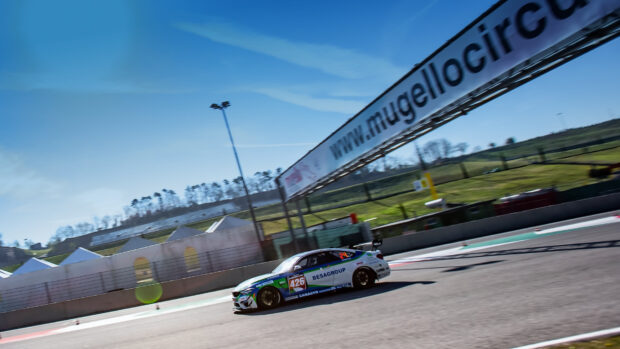 A racing car with number 426 speeds along the race track under clear blue skies, 4K Desktop Wallpaper