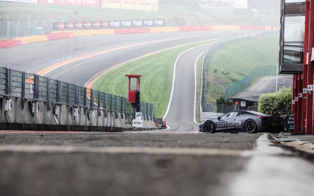A sports car is parked near the pit lane on the race track with green grassy surroundings, HD Desktop Wallpaper