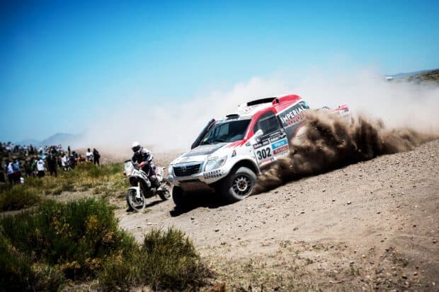 A rally raid vehicle kicks up dust while racing on rough terrain, 2K Desktop Wallpaper