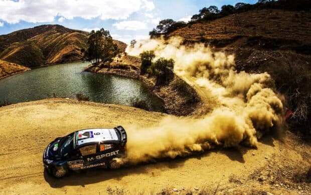 A Rally Raid car kicks up dust while drifting on a winding mountain dirt road, HD Desktop Wallpaper