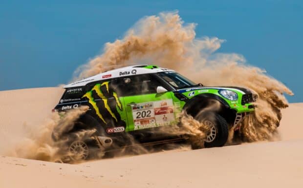 A rally raid car is speeding through the desert sand with dust clouds behind it, HD Desktop Wallpaper