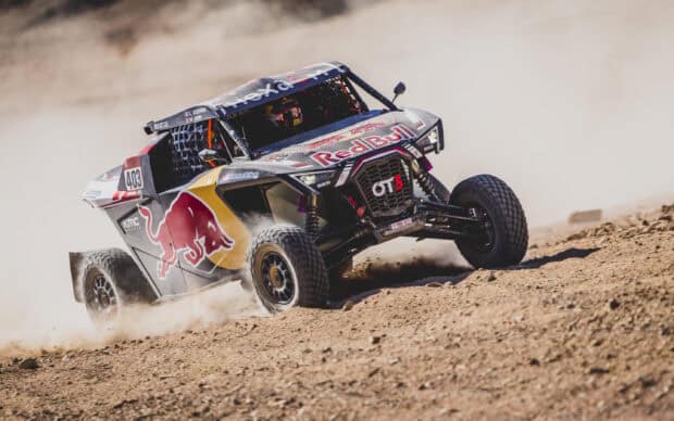 A rally raid car races quickly on dusty, uneven desert terrain, 2K Desktop Wallpaper