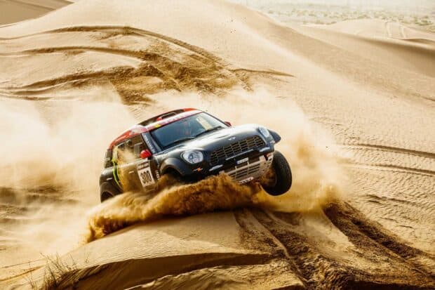 A rally raid car kicking up sand while racing across desert dunes, HD Desktop Wallpaper
