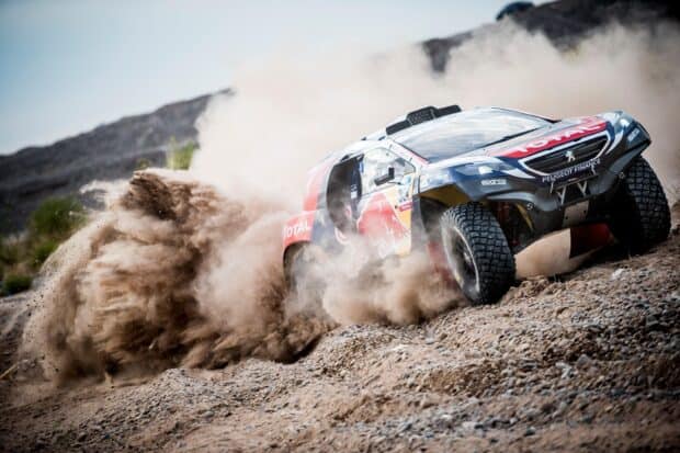 A rally raid vehicle kicks up dust while racing on a rocky terrain, 2K Desktop Wallpaper