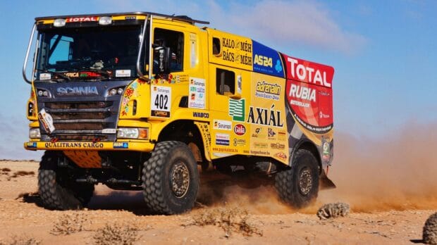 A yellow rally raid truck races across the sandy desert kicking up dust, HD Desktop Wallpaper