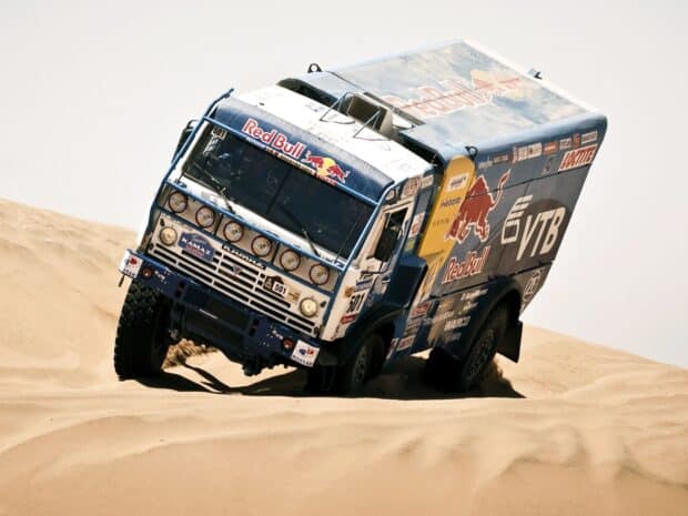 A rally raid truck is navigating through sandy desert dunes during an intense race, HD Desktop Wallpaper