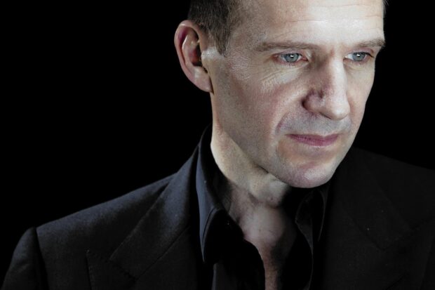 Ralph Fiennes looks thoughtful with a black suit against a dark background, HD Desktop Wallpaper