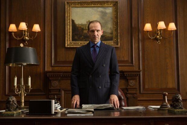 Ralph Fiennes stands confidently behind a desk in a wood paneled office, HD Desktop Wallpaper