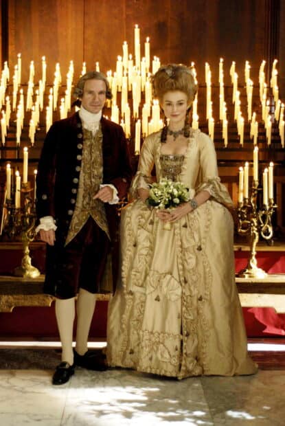 Ralph Fiennes stands beside a woman in an ornate dress with lit candles behind them, 2K Mobile Wallpaper