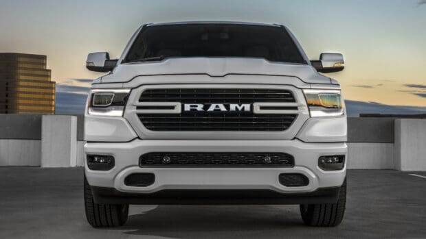 A white Ram truck is parked with a sunset in the background featuring buildings and a clear sky, HD Desktop Wallpaper