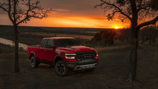 A red Ram truck is parked near trees with the sunset in the background, 2K Desktop Wallpaper