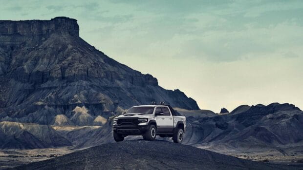 A Ram truck is parked on a rocky hill with mountainous terrain in the background, 2K Desktop Wallpaper