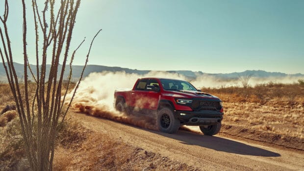 A red Ram truck is driving on a dusty desert road with mountains in the background, 4K Desktop Wallpaper