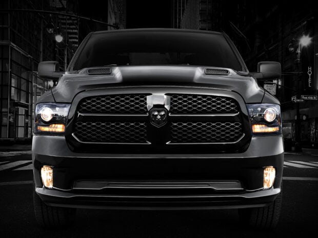 A powerful Ram truck is shown from the front with headlights on in a city street setting, HD Desktop Wallpaper