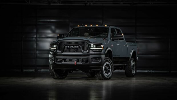 A Ram truck is displayed with strong lighting in a dark garage setting, HD Desktop Wallpaper