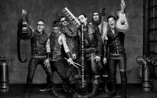 The Rammstein band poses intensely wearing distinctive outfits and holding instruments, 2K Desktop Wallpaper