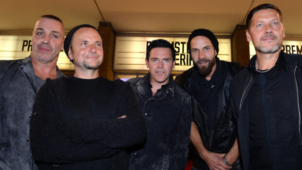 The Rammstein band members stand closely together wearing dark outfits, 2K Desktop Wallpaper