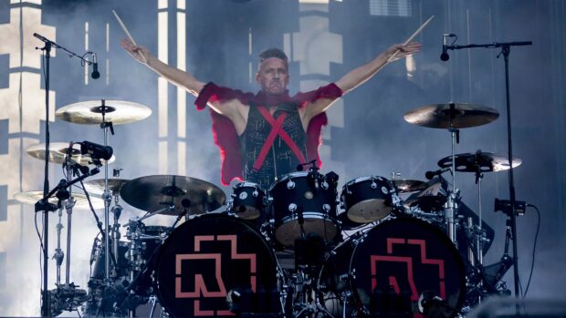 The Rammstein drummer raises his arms while playing on the drum set during a live show, 4K Desktop Wallpaper