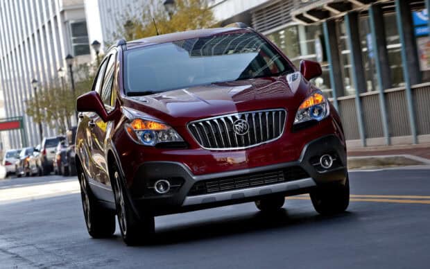 A red Buick Encore is driving down an urban street with buildings in the background, HD Desktop Wallpaper