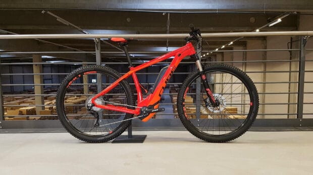 A red Cube bike is shown parked indoors with a industrial background, HD Desktop Wallpaper