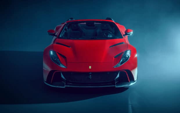 A red Ferrari 812 GTS sports car is shown from a front angle in a dark studio, 2K Desktop Wallpaper