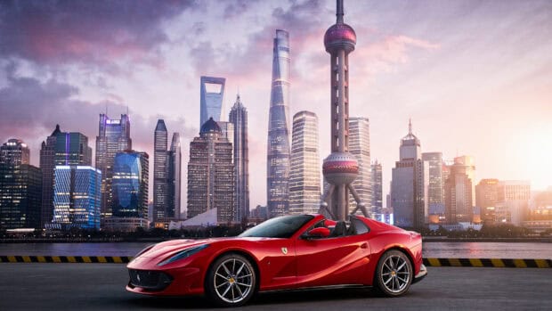 A red Ferrari 812 GTS is parked with a city skyline at sunset in the background, 4K Desktop Wallpaper