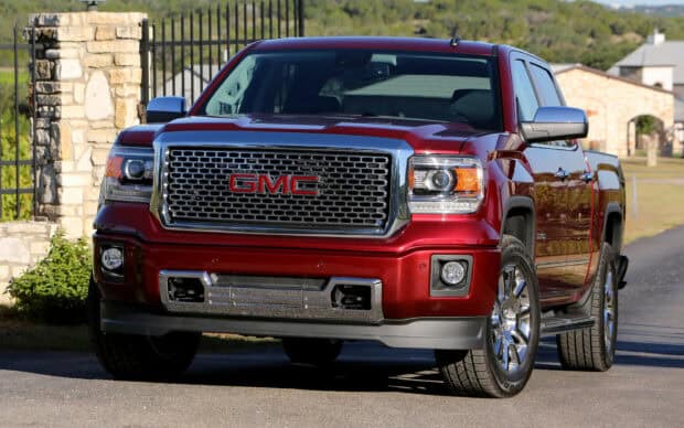 A red GMC Sierra truck is parked on a driveway with clear details of the grille and headlights, HD Desktop Wallpaper