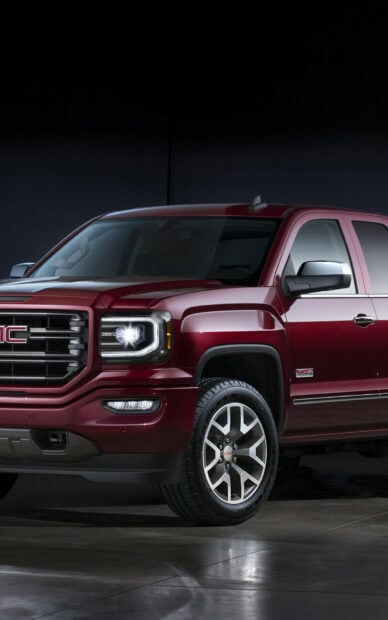 The red GMC Sierra is parked indoors showing its front and side exterior details, HD Mobile Wallpaper