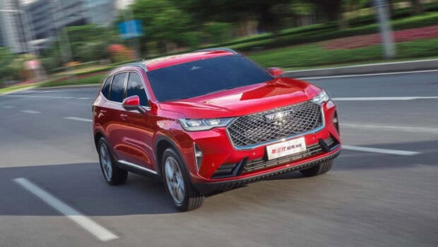 A red Great Wall Motors car is driving smoothly on an urban street with greenery in the background, HD Desktop Wallpaper
