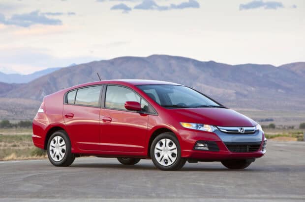 A red Honda Insight parked on a road with mountains in the background under a cloudy sky, HD Desktop Wallpaper